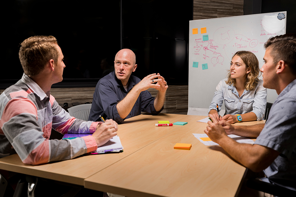 four students sitting at a round table having a discussion